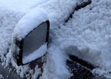 Kışın karla kaplı siyah bir arabanın yan aynasına yaklaş. 