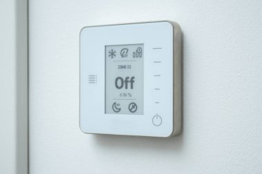Beyaz duvarda modern bir elektrikli termostat kontrol sistemi var. Ev konseptinde klima 
