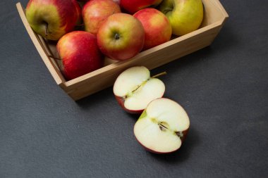 Koyu gri masa arkaplanındaki ahşap sandıkta taze, küçük organik kırmızı elmalar.