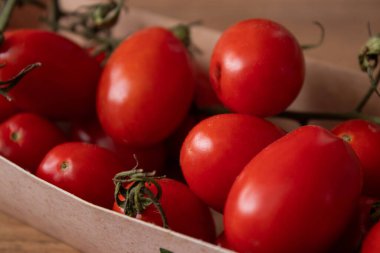 Mutfak masasındaki eko karton kutuda organik kırmızı kiraz domateslerini kapatın.