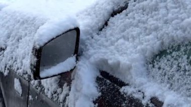 Kışın karla kaplı siyah bir arabanın yan aynasına yaklaş. 