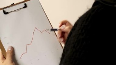 Çalışan kadınların ellerini kapatın ve kağıt panoya çizgi diyagramını gösterin. Ofis konseptinde iş raporu