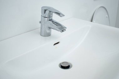 Kireçtaşı lekeli ve kirli beyaz lavabolu banyo musluğunu kapat. Ev işleri konsepti 