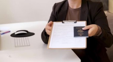 Vize başvuru belgelerini elinde tutan bir kadın ve Amerikan pasaportu, beyaz ofis masası. Yüksek kaliteli FullHD görüntüler