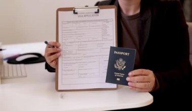 Ofis masasında Amerikan pasaportu olan beyaz bir kadının vize başvuru formlarını doldurması. Yüksek kaliteli FullHD görüntüler