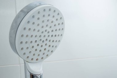 Modern bir duş başlığının, kireç boyası lekeleri, beyaz kiremit duvar arkaplanı.