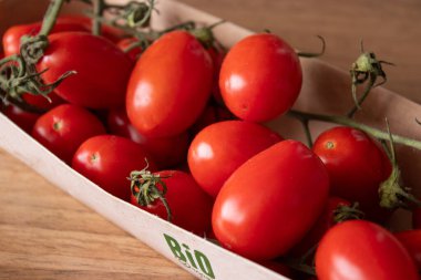 Mutfak masasındaki eko karton kutuda organik kırmızı kiraz domateslerini kapatın.