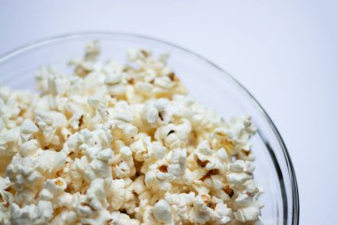 Beyaz masa arkasındaki cam kasede lezzetli patlamış mısır..