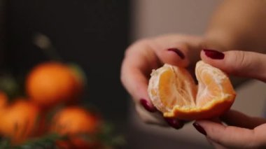 Kırmızı tırnaklı, olgun bir mandalina meyvesini soyan kadın ellerini kapatın. Yüksek kaliteli FullHD görüntüler