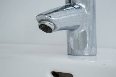Kireçtaşı lekeli ve kirli beyaz lavabolu banyo musluğunu kapat. Ev işleri konsepti 