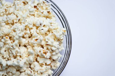 Beyaz masa arkasındaki cam kasede lezzetli patlamış mısır..