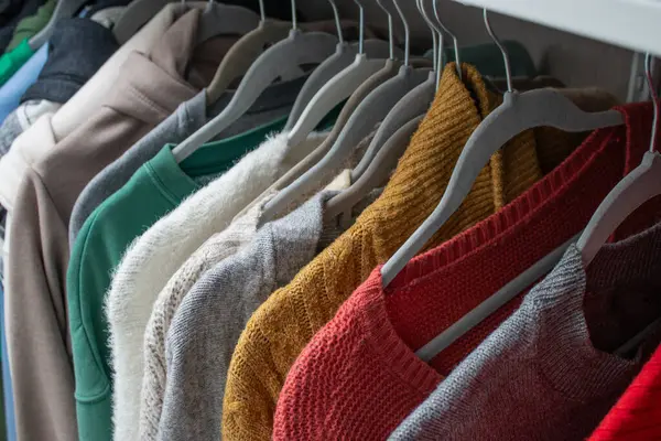 Kadın sonbaharını ve kışları dolaptaki askıların üzerine sıcak örülmüş kumaşları kapatın. Rahat ve renkli kostüm konsepti
