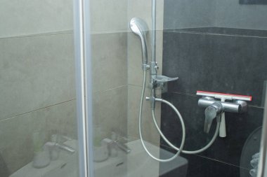 Duşta kireçtaşı lekeleri olan bir duş başlığını kapat, gri kiremit duvarlı.