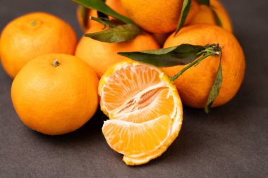 Soyulmuş mandalina dilimlerini kapatın ve tüm mandalinaları gri masa arkasına yığın 