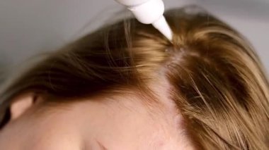 Kafasına serum uygulayan beyaz bir şişeyle sarı saçlı bir kadının fotoğrafını çek. Yüksek kaliteli FullHD görüntüler