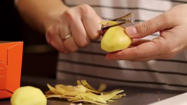 Kadın ellerinin, çiğ sarı patatesi, gri mutfak tezgahı masasını soyarken yavaş çekimde yaklaş. Yüksek kaliteli FullHD görüntüler