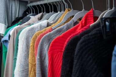 Kadın sonbaharını ve kışları dolaptaki askıların üzerine sıcak örülmüş kumaşları kapatın. Rahat ve renkli kostüm konsepti