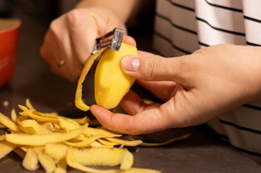 Kadın ellerini kapat. Çiğ sarı patates, bulanık beyaz gömlek arka planı. 