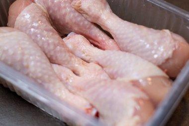 Mutfak masasındaki plastik bir kutunun içinde çiğ tavuk budu kapatıyoruz. Yemek için et hazırlıyoruz. 