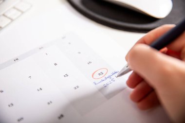 23 Şubat 'ı işaret eden bir kadın eli. Beyaz ofis masasında bir Alman takviminde seçim günü.