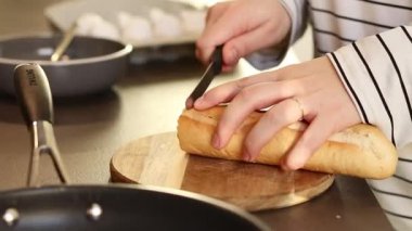 Kadın elinin ahşap kesim tahtasıyla ekmeği kesmesini. Evde yemek hazırlıyorum. Yüksek kaliteli FullHD görüntüler