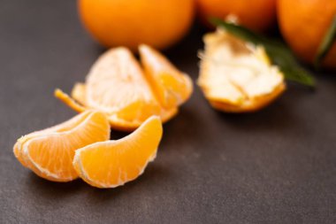 Soyulmuş mandalina dilimlerini kapatın ve tüm mandalinaları gri masa arkasına yığın 