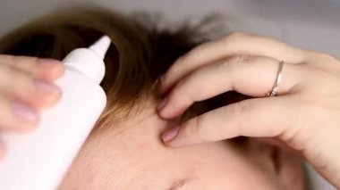 Kafasına serum uygulayan beyaz bir şişeyle sarı saçlı bir kadının fotoğrafını çek. Yüksek kaliteli FullHD görüntüler