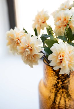 Evdeki pencere pervazında duran bir vazoda güzel bej çiçekleri kapat.