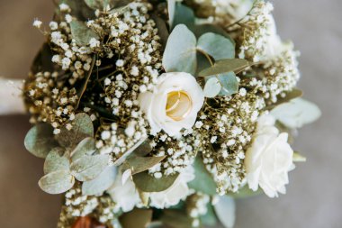 Beyaz çiçekli güzel bukette altın bir düğün ve gri masada bir gelin okaliptüsü. 