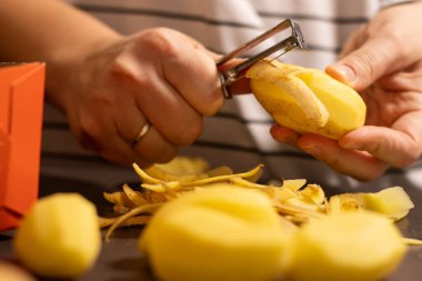 Kadın ellerini kapat. Çiğ sarı patates, bulanık beyaz gömlek arka planı. 