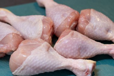 Çiğ tavuk budu, mutfak masasındaki yeşil plastik kesme tahtasının üzerinde, et pişirmek için hazırlanıyor. 