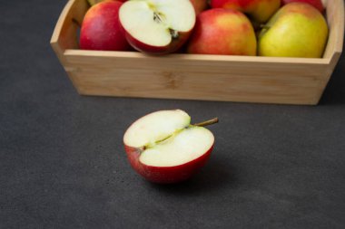 Koyu gri masa arkaplanındaki ahşap sandıkta taze, küçük organik kırmızı elmalar.