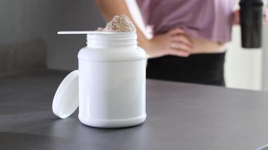 Protein tozu kutusunu ve masadaki pembe dambılları kapatın. Kadın protein içeceği hazırlıyor. Kilo vermenin yerine diyet yemeği. - Evet. Yüksek kaliteli FullHD görüntüler