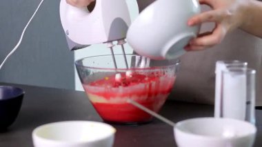 Evdeki kırmızı kadife pastayı hazırlamak için cam bir kasenin içindekileri el çırpma makinesiyle karıştırıyorum. Yüksek kaliteli FullHD görüntüler