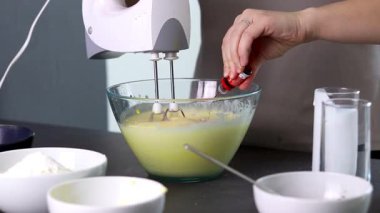 Evdeki kırmızı kadife pastayı hazırlamak için cam bir kasenin içindekileri el çırpma makinesiyle karıştırıyorum. Yüksek kaliteli FullHD görüntüler