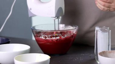 Evdeki kırmızı kadife pastayı hazırlamak için cam bir kasenin içindekileri el çırpma makinesiyle karıştırıyorum. Yüksek kaliteli FullHD görüntüler