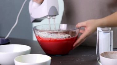Evdeki kırmızı kadife pastayı hazırlamak için cam bir kasenin içindekileri el çırpma makinesiyle karıştırıyorum. Yüksek kaliteli FullHD görüntüler