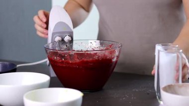Evdeki kırmızı kadife pastayı hazırlamak için cam bir kasenin içindekileri el çırpma makinesiyle karıştırıyorum. Yüksek kaliteli FullHD görüntüler