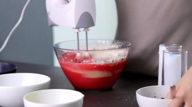 Evdeki kırmızı kadife pastayı hazırlamak için cam bir kasenin içindekileri el çırpma makinesiyle karıştırıyorum. Yüksek kaliteli FullHD görüntüler