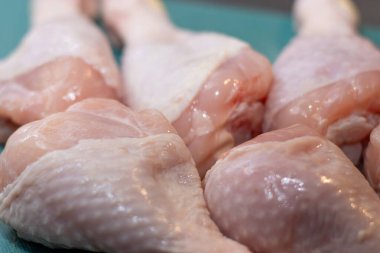 Çiğ tavuk budu, mutfak masasındaki yeşil plastik kesme tahtasının üzerinde, et pişirmek için hazırlanıyor. 