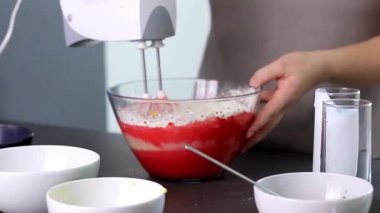 Evdeki kırmızı kadife pastayı hazırlamak için cam bir kasenin içindekileri el çırpma makinesiyle karıştırıyorum. Yüksek kaliteli FullHD görüntüler