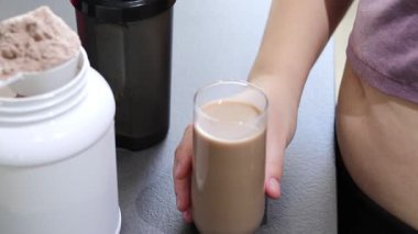 Mutfakta protein içeceği hazırlayan kadına yakın çekim. Kilo vermenin yerine diyet yemeği. Masada beyaz beyaz protein tozu kutusu var. Yüksek kaliteli FullHD görüntüler