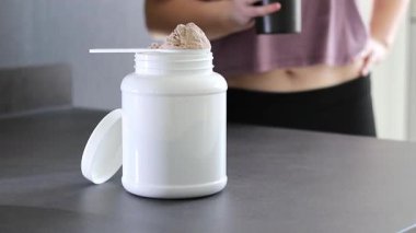Protein tozu kutusunu ve masadaki pembe dambılları kapatın. Kadın protein içeceği hazırlıyor. Kilo vermenin yerine diyet yemeği. - Evet. Yüksek kaliteli FullHD görüntüler