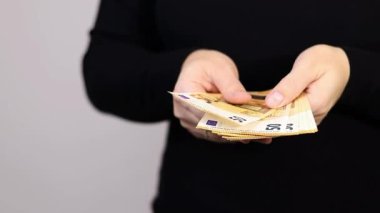 Elli avroluk nakit para tutan, siyah gömlek giyen, arka planda fotokopi alanı olan gri bir kadın. Yüksek kaliteli FullHD görüntüler