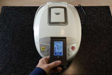 Elektrikli multicooker 'dan gelen elektromanyetik radyasyon. Bir Avrupalının eli ölçmek için bir cihaz tutar
