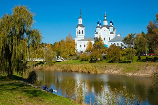 stock image Horishni Plavni city, Ukraine - October 16, 2022: Pedestrian bridge across the pond and St. Nicholas Orthodox Cathedral. Nature of Ukraine on an autumn sunny day