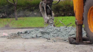 Traktör matkabı bir yaz günü beton kırıyor. Anıtın yıkımı. İnşaat alanında ekipman işi.