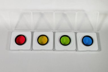 Beyaz arkaplandaki kutulardaki optik ışık filtreleri. Bir optik bilimsel enstrüman ya da kamera için aksesuar ve parça