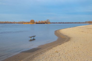 Dinyeper nehrindeki su seviyesi yükseldi. Sahada tahta bir bank suyun içinde duruyor. Orman ufukta sonbahar günü