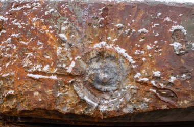 The tank's armor was damaged after being hit by a shell. Projectile impact site. Rusty military vehicle metal surface